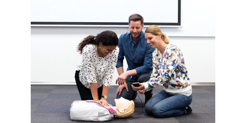 Student practicing CPR on a Little Anne manikin with 2 instructors