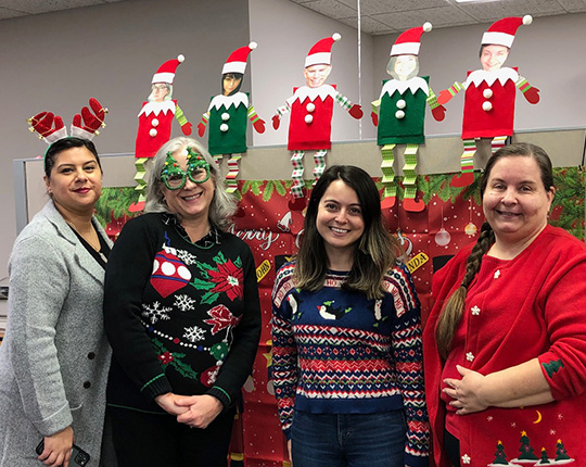 WorldPoint employees standing in front of their holiday-decorated work space