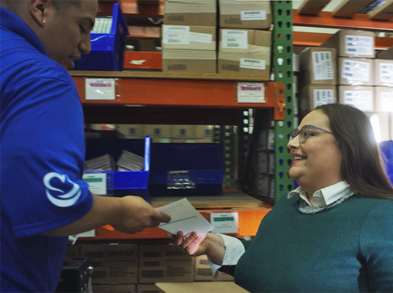 Female WorldPoint Employee handing a packing slip to a male warehouse employee
