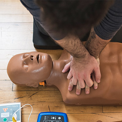 Man performing CPR on CPR Taylor manikin
